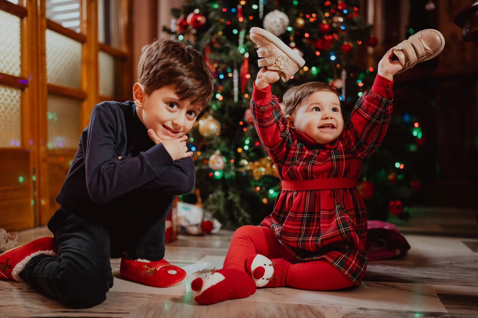 Garçon et petite sœur en tenue écossaise devant le sapin illuminé