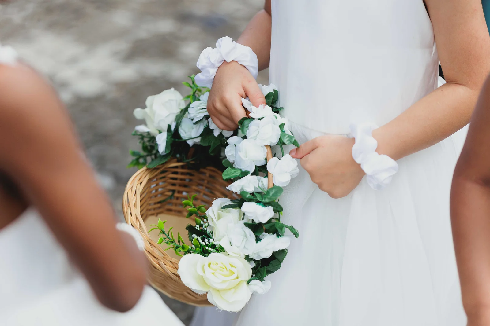 Détail d'une robe de cérémonie blanche de fille, panier de fleurs à la main