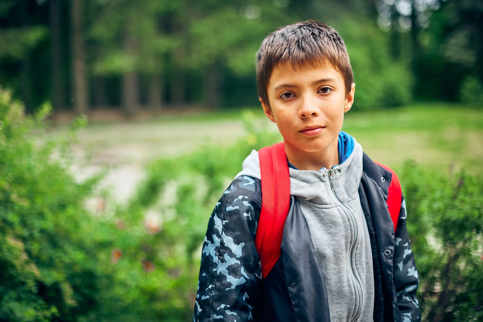 Garçon en sweat à capuche avec un sac à dos rouge, sur le chemin de l'école