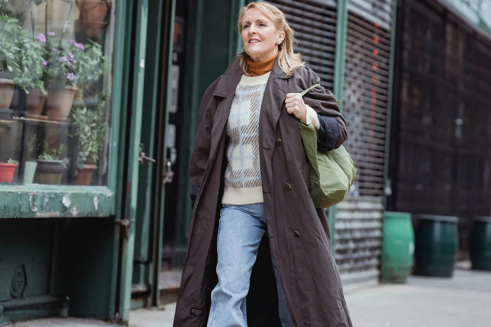 Manteau long marron chocolat ouvert sur une maille écrue et un jean